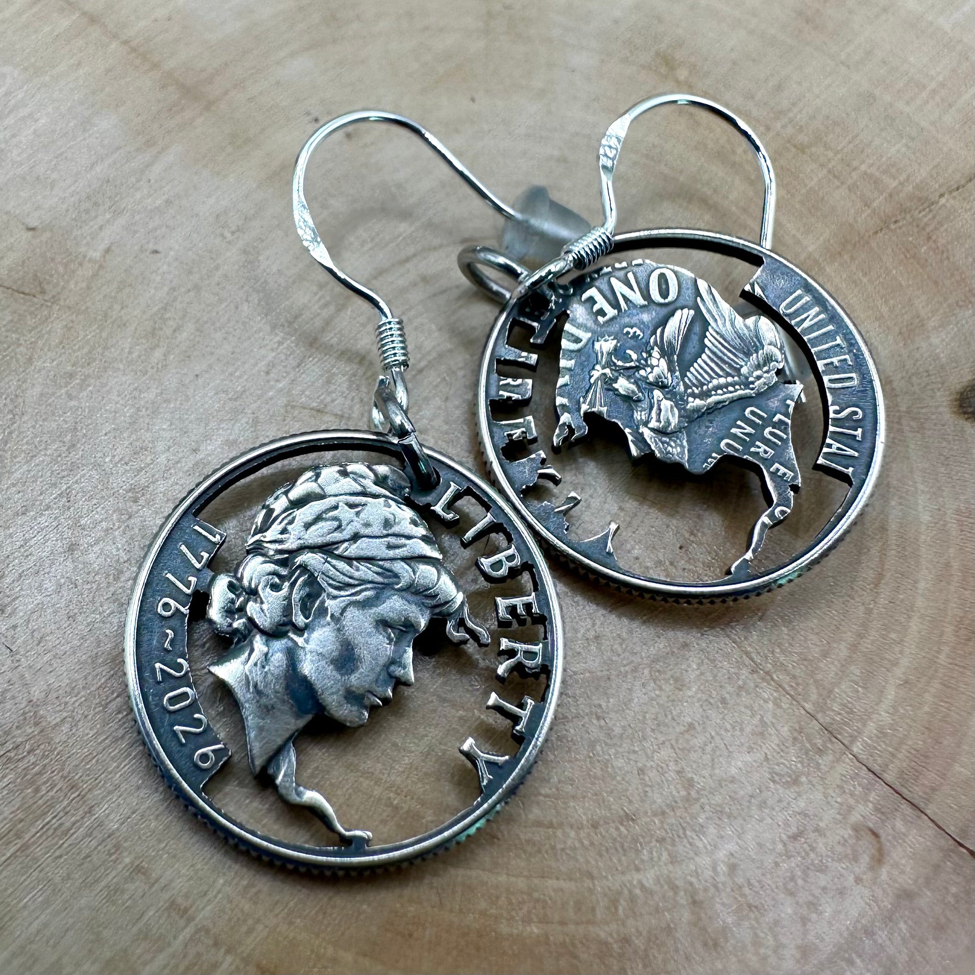 U.S. 2026 "Lady Liberty" Dime Hand Cut Coin Earrings on a wood round. -Mountainstruck Coin Jewelry