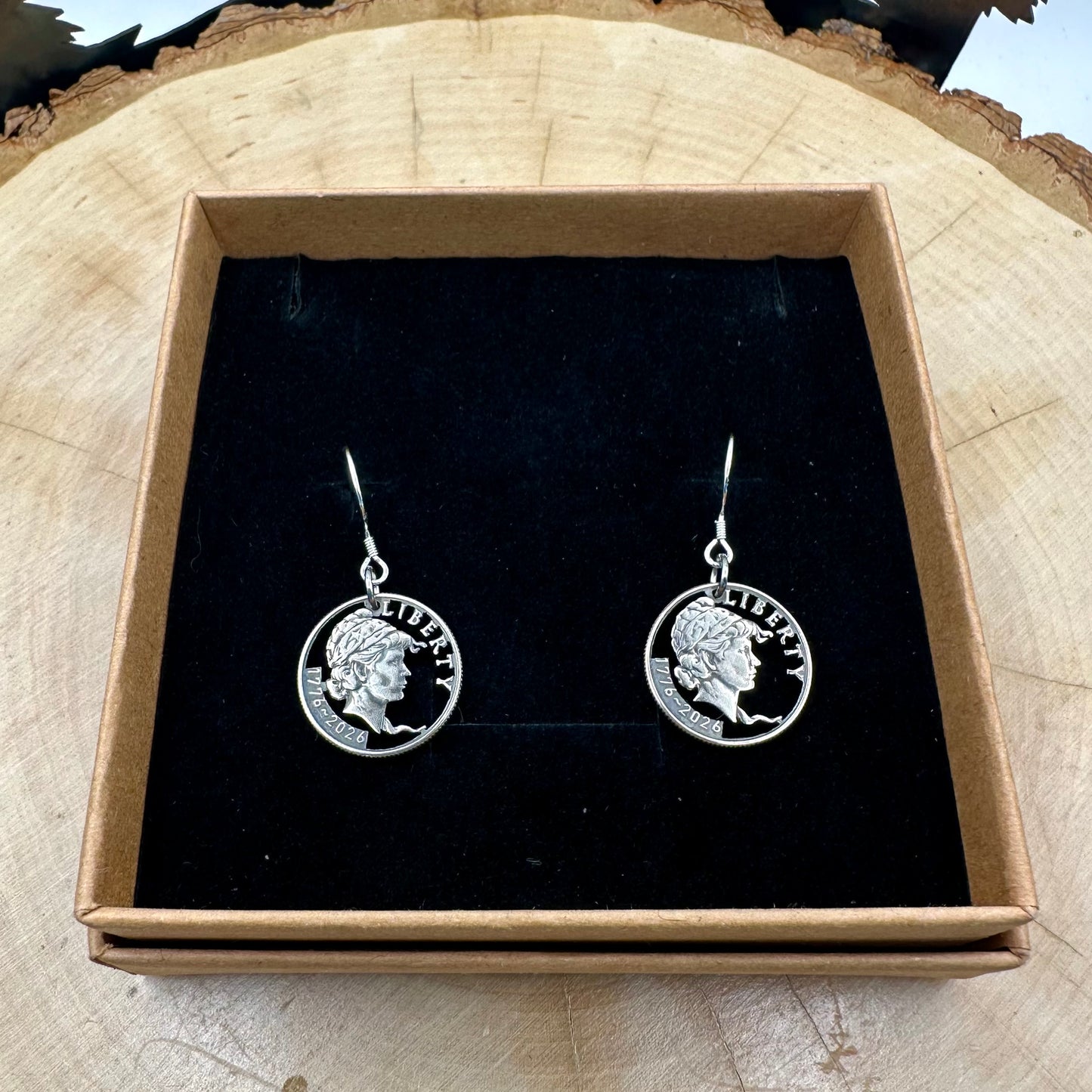 U.S. 2026 "Lady Liberty" Dime Hand Cut Coin Earrings on a black velvet background in a brown kraft box on a wood round. -Mountainstruck Coin Jewelry