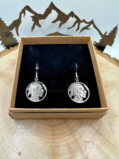 U.S. Buffalo Nickel Hand Cut Coin Earrings (Front) in a brown kraft box on black velvet background on top of a light wood round with a metal mountain and tree display. - Mountainstruck Coin Jewelry