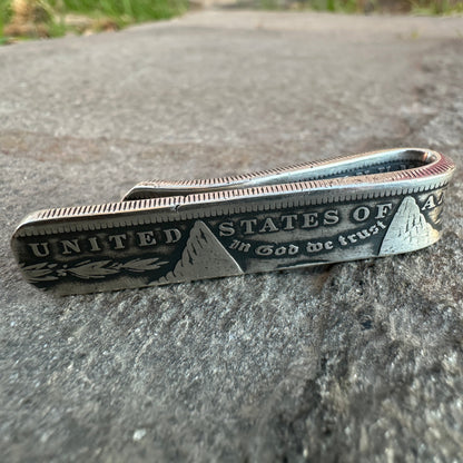 U.S. Morgan Dollar Silver Coin Money Clip on a textured rock with grass in the background.
- Mountainstruck Coin Jewelry