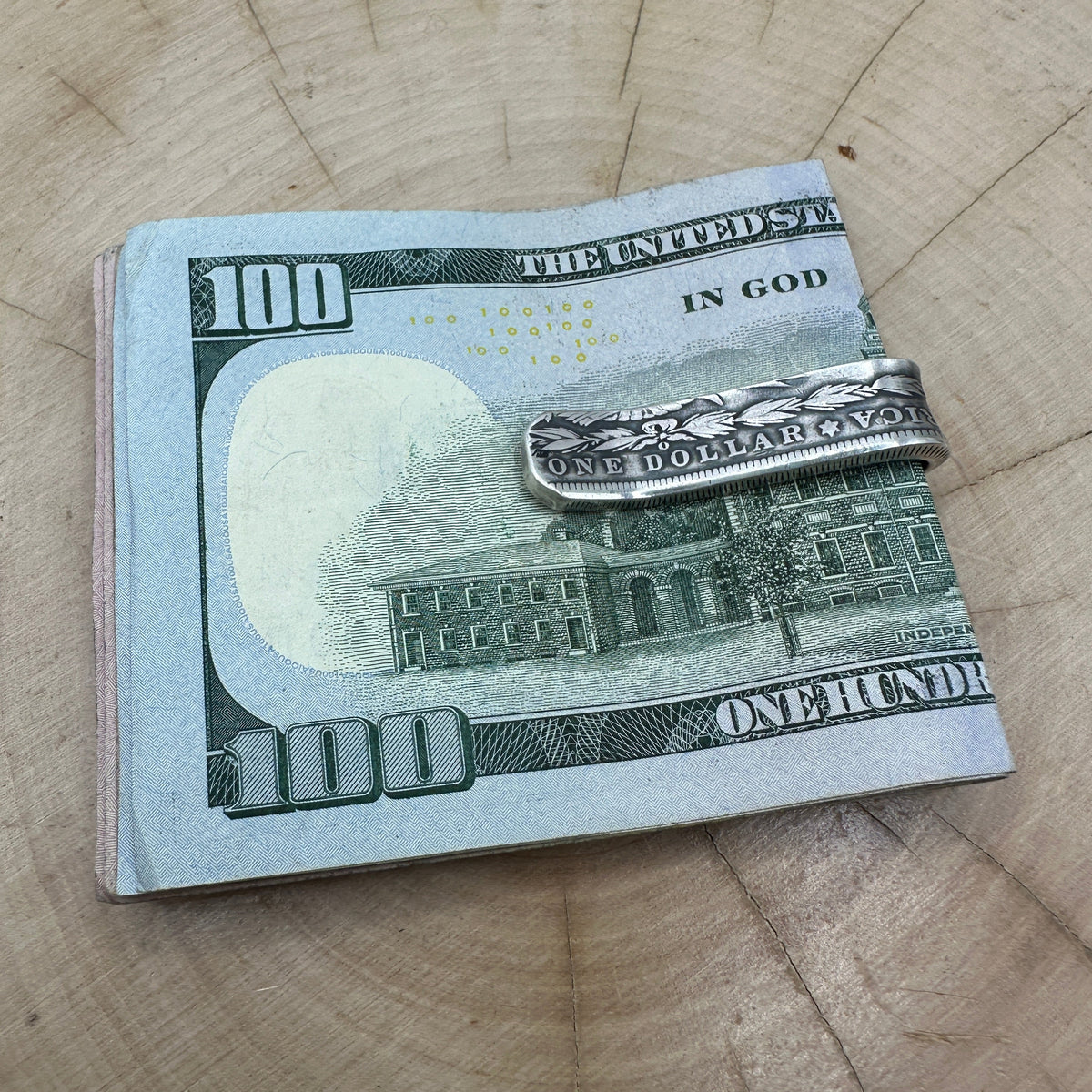 U.S. Morgan Dollar Silver Coin Money Clip holding money on a light wood round.
- Mountainstruck Coin Jewelry