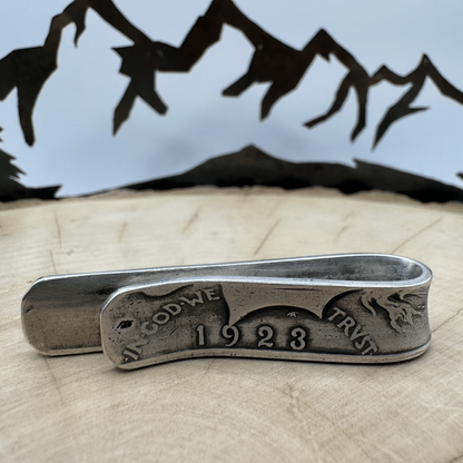 U.S. Peace Dollar Silver Coin Money Clip on a light wood round with a hand cut metal mountain background.
- Mountainstruck Coin Jewelry