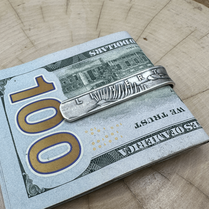 U.S. Peace Dollar Silver Coin Money Clip with money in clip on a light wood round with a hand cut metal mountain background.
- Mountainstruck Coin Jewelry