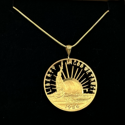 24k Plate Nation of Immigrants Cut Half Dollar Coin Necklace on a black velvet background. - Mountainstruck Coin Jewelry