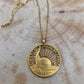 24k Plate Nation of Immigrants Cut Half Dollar Coin Necklace on a wood background. - Mountainstruck Coin Jewelry
