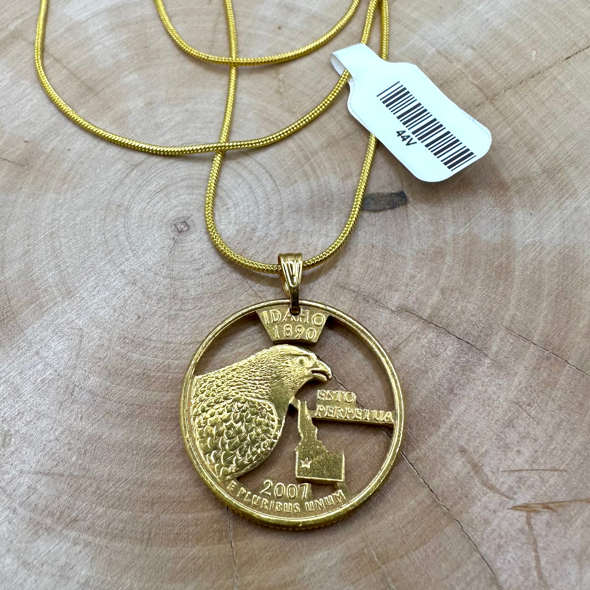 U.S. Idaho State Quarter Hand Cut Coin Necklace 24k gold plated with a snake chain on a wood background. - Mountainstruck Coin Jewelry