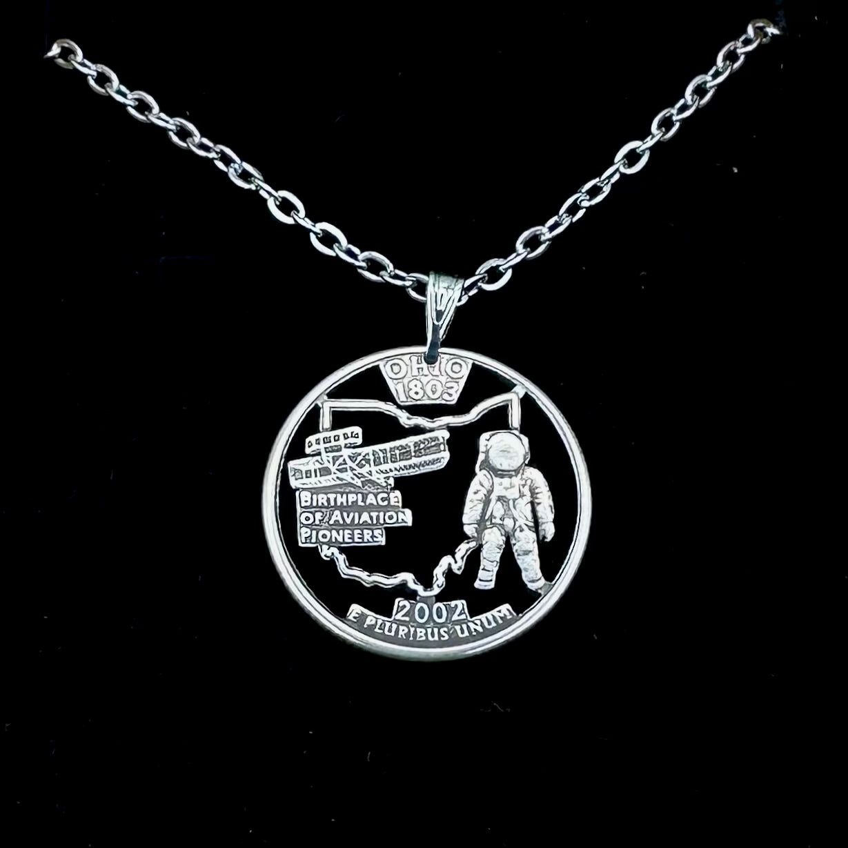 U.S. Ohio State Quarter Hand Cut Coin Necklace with a stainless chain on a black velvet background. - Mountainstruck Coin Jewelry