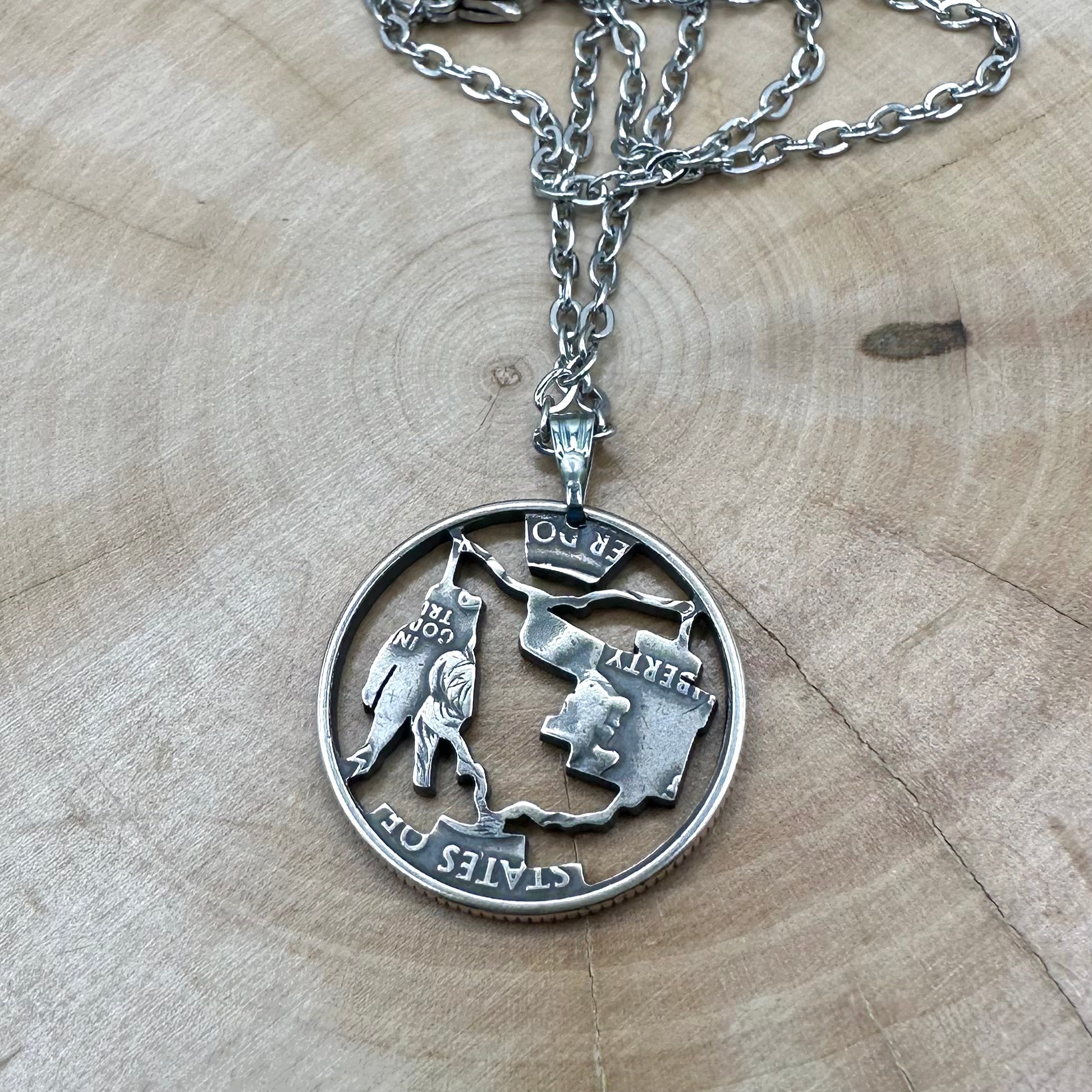 U.S. Ohio State Quarter Hand Cut Coin Necklace back with a stainless steel chain on a wood background. - Mountainstruck Coin Jewelry