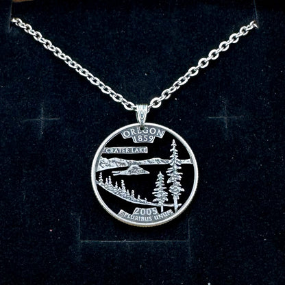 U.S. Oregon State Quarter Hand Cut Coin Necklace with a stainless chain on a black velvet background. - Mountainstruck Coin Jewelry