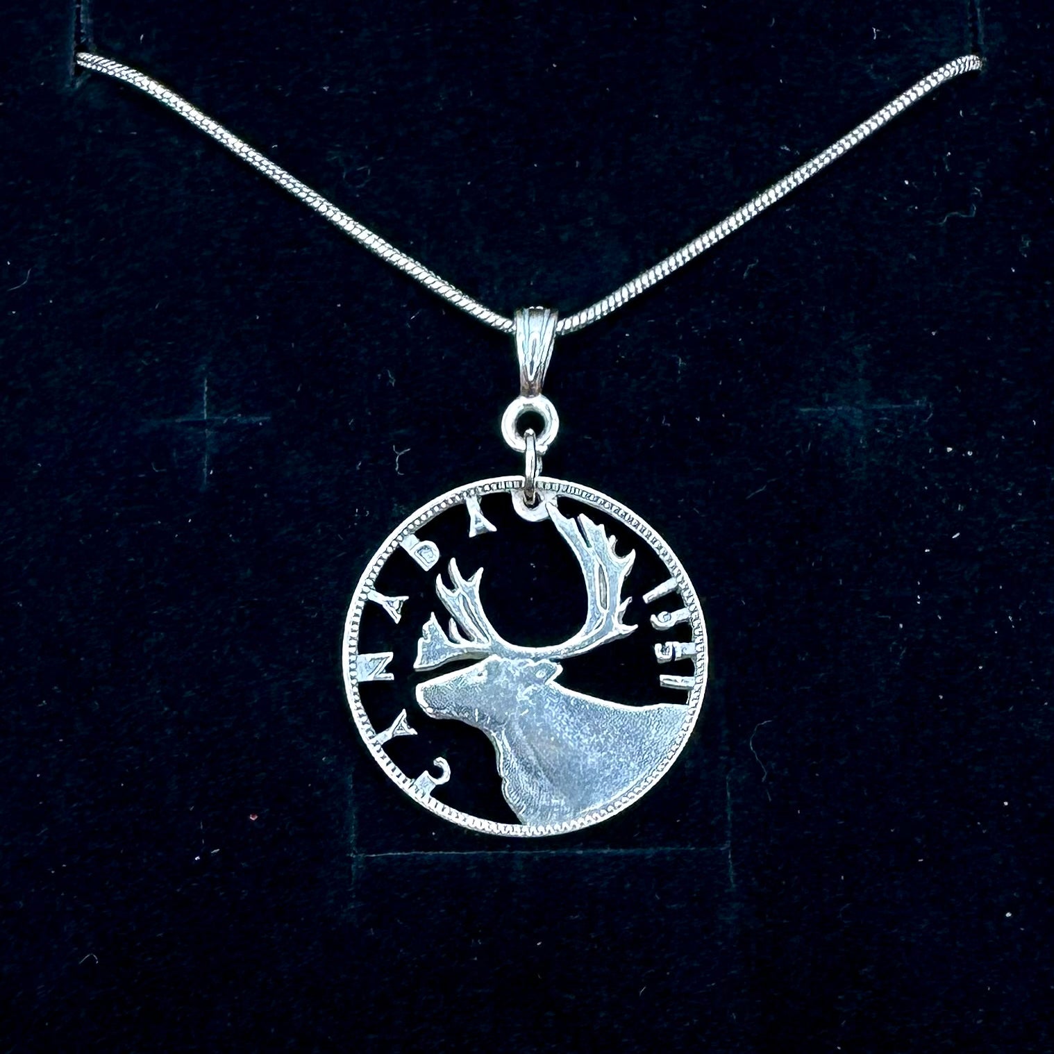 Caribou Canada Silver 25 Cent Hand Cut Coin Necklace on a black velvet  background. - Mountainstruck Coin Jewelry