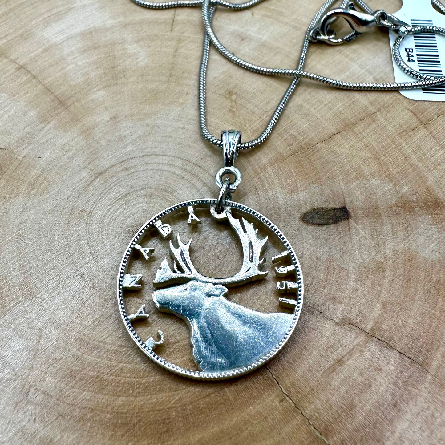 Caribou Canada Silver 25 Cent Hand Cut Coin Necklace on a light wood round. - Mountainstruck Coin Jewelry