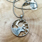 Caribou Canada Silver 25 Cent Hand Cut Coin Necklace back on a light wood round. - Mountainstruck Coin Jewelry
