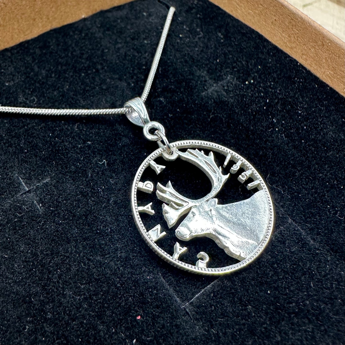 Caribou Canada Silver 25 Cent Hand Cut Coin Necklace on a black velvet  background in a brown kraft box. - Mountainstruck Coin Jewelry