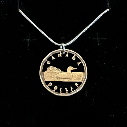 Canadian Loonie 1 Dollar Hand Cut Coin Necklace with a snake chain on a black velvet background. - Mountainstruck Coin Jewelry