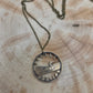 Canadian Loonie 1 Dollar Hand Cut Coin Necklace with bronze chain on a wood background. - Mountainstruck Coin Jewelry