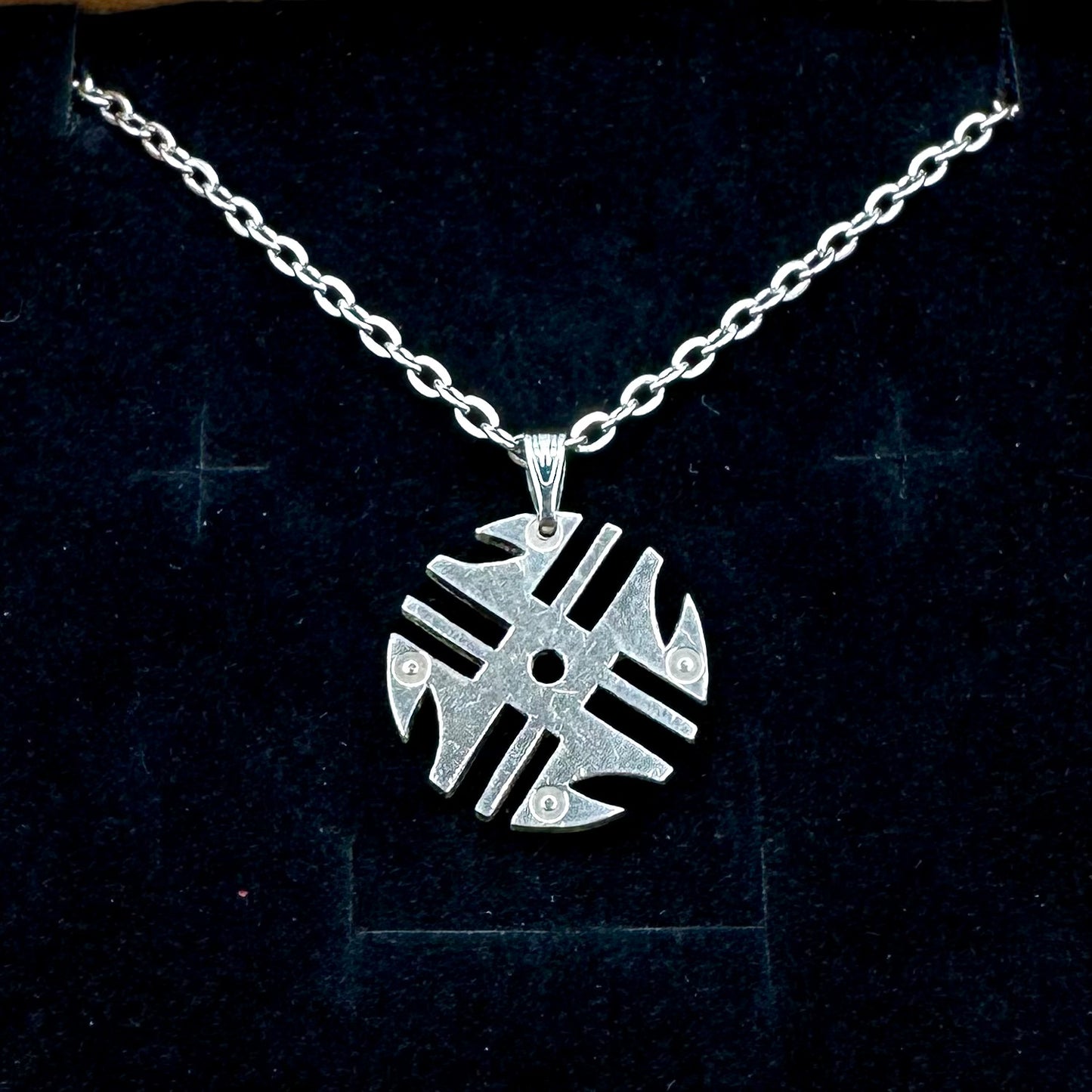 Columbia 200 Pesos Quimbaya Spindle Wheel Hand Cut Coin Necklace with a stainless chain on a black velvet background. - Mountainstruck Coin Jewelry