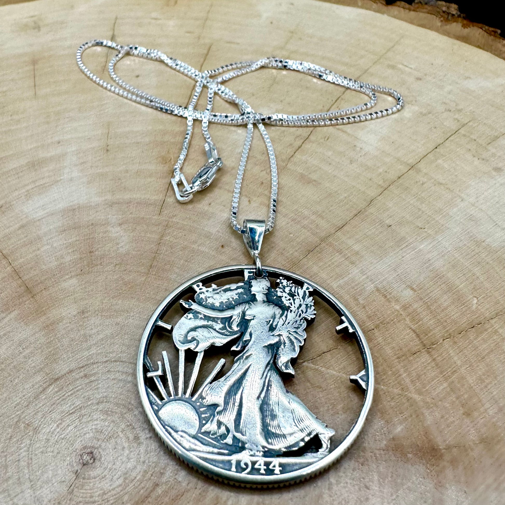 U.S. Walking Liberty Hand Cut Silver Coin Necklace with a snake chain on a light wood round. - Mountainstruck Coin Jewelry