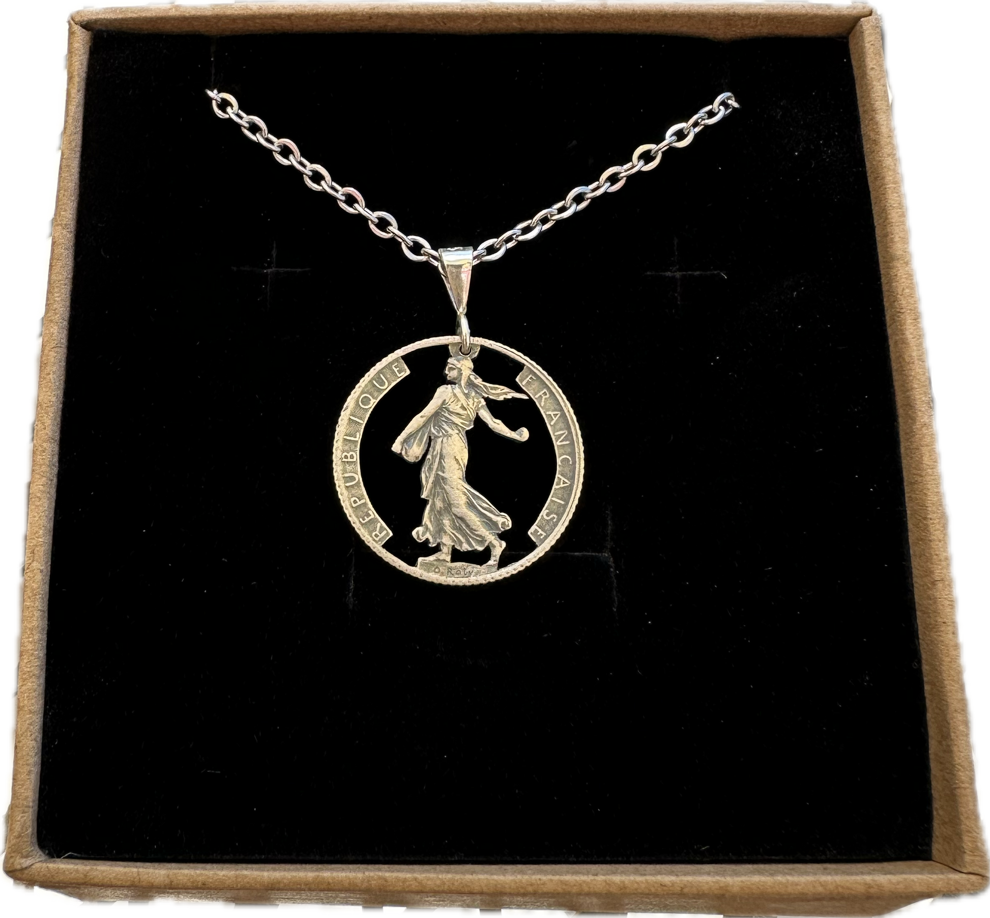 France 1 Franc Silver Hand Cut Coin Necklace in a brown kraft box on a black velvet background. - Mountainstruck Coin Jewelry