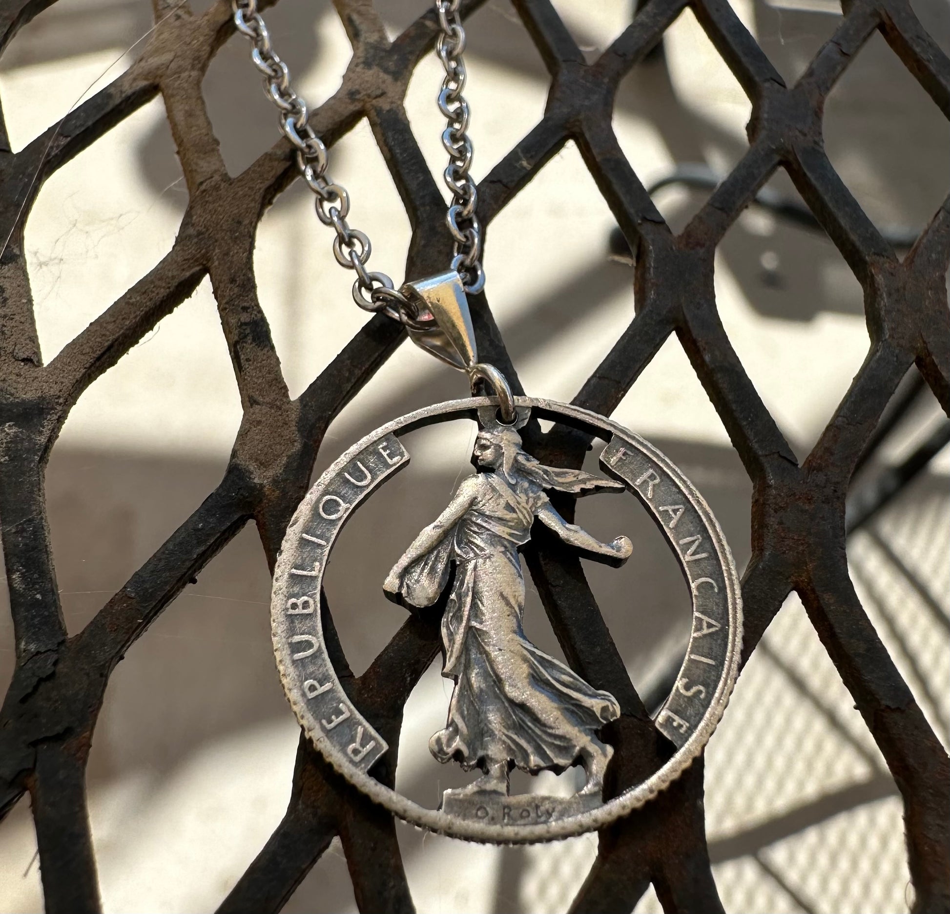 France 1 Franc Silver Hand Cut Coin Necklace on a diamond shaped metal background. - Mountainstruck Coin Jewelry