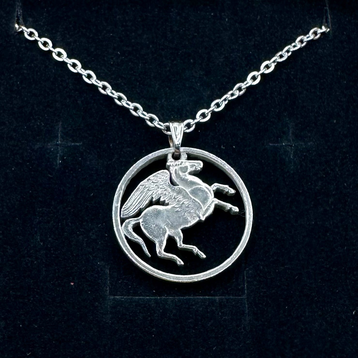 Greece Pegasus 5 Drachmai Hand Cut Coin Necklace with a stainless chain on a black velvet background. - Mountainstruck Coin Jewelry