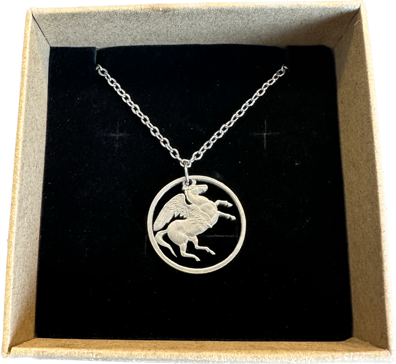 Greece Pegasus 5 Drachmai Hand Cut Coin Necklace with a stainless chain in a brown kraft box on a black velvet background. - Mountainstruck Coin Jewelry