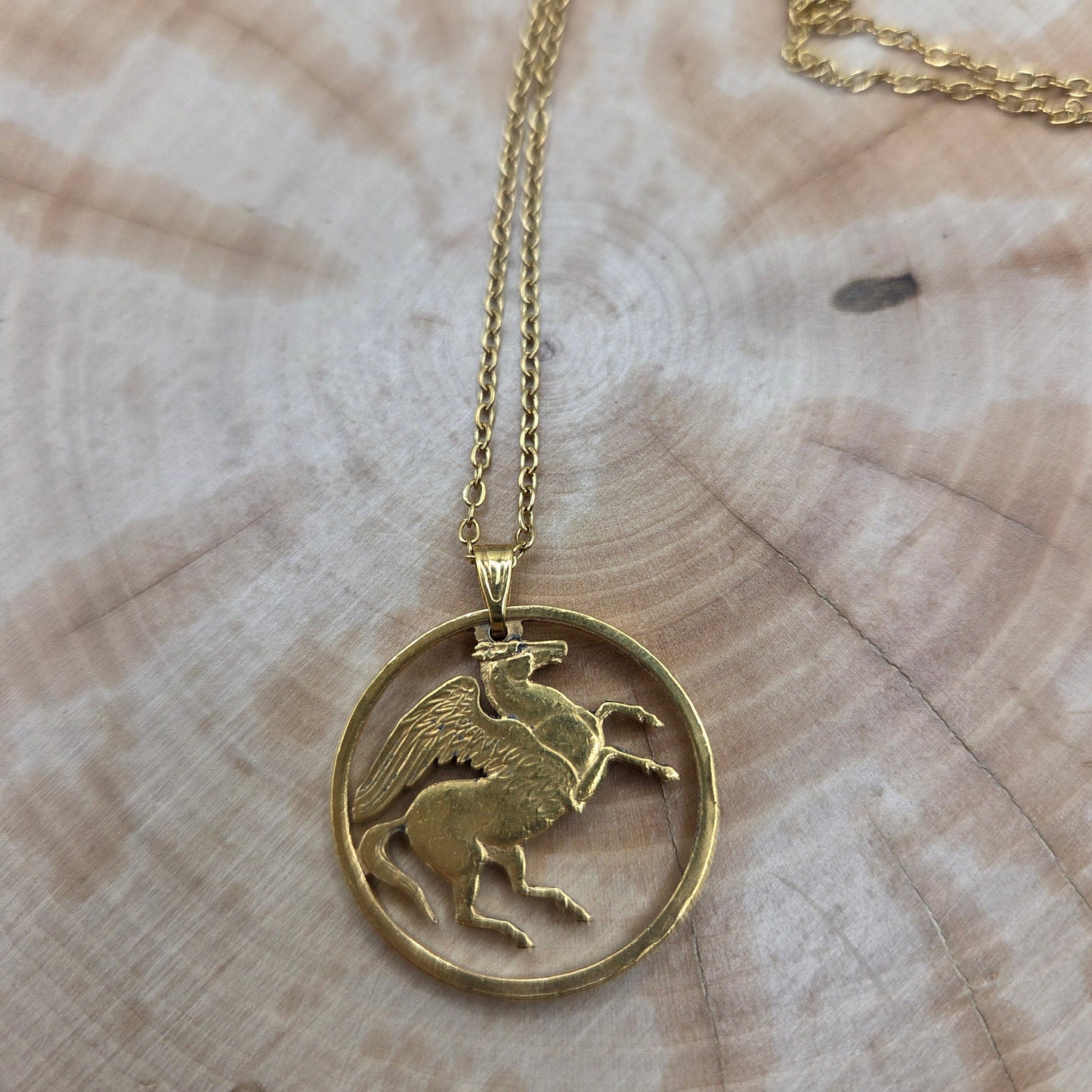 Greece Pegasus 5 Drachmai Hand Cut Coin Necklace gold plated with a gold plated chain on a wood background. - Mountainstruck Coin Jewelry