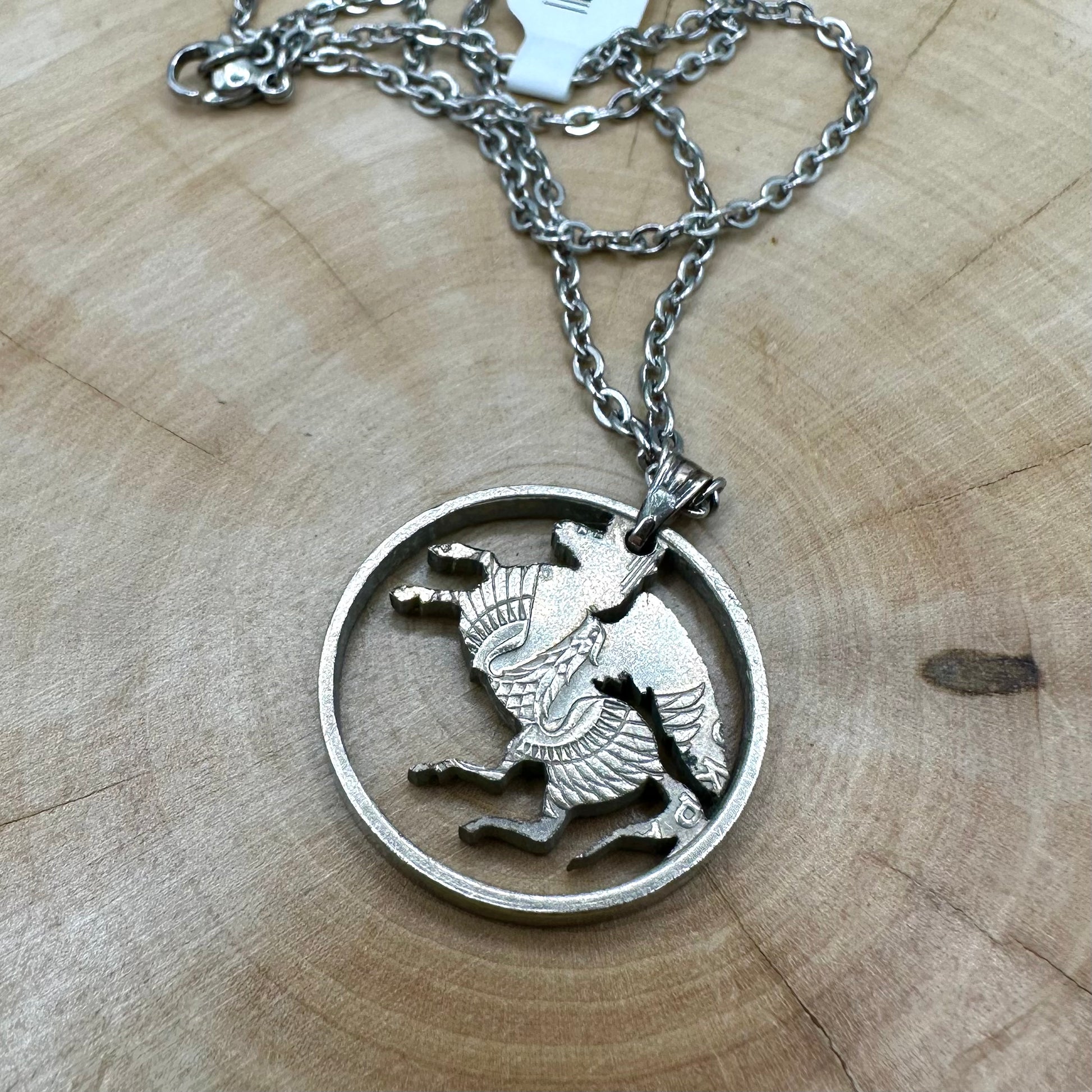 Greece Pegasus 5 Drachmai Hand Cut Coin Necklace back with a stainless chain on a wood background. - Mountainstruck Coin Jewelry
