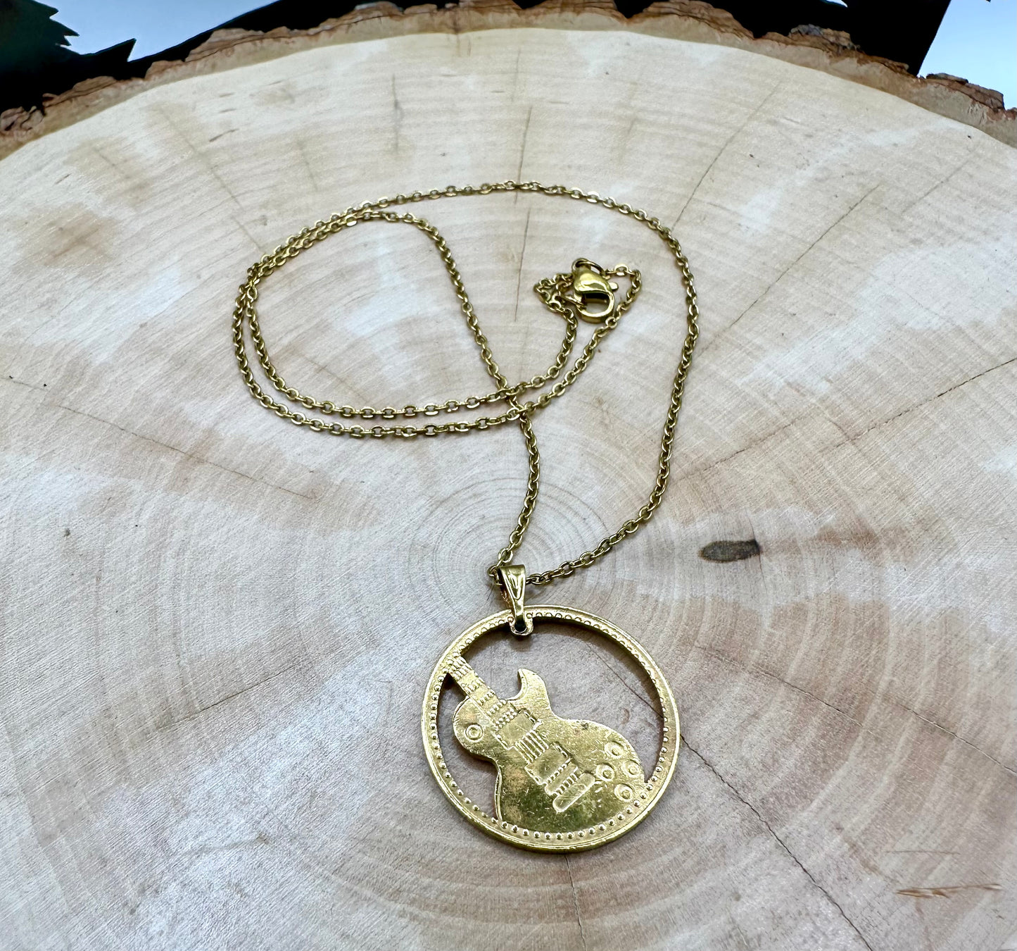Guitar Hand Cut Token Necklace on a light wood round. - Mountainstruck Coin Jewelry