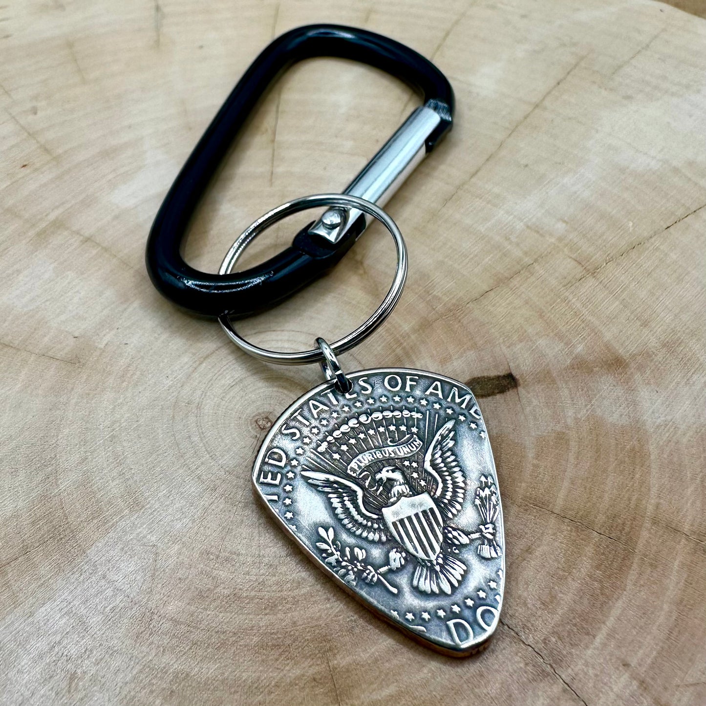 Guitar Pick U.S. Half Dollar Keychain with a black carabiner on a light wood round. - Mountainstruck Coin Jewelry