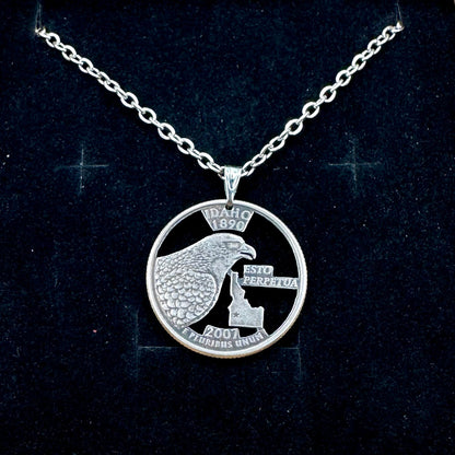Idaho State Quarter Hand Cut Coin Necklace with a stainless chain on a black velvet background. - Mountainstruck Coin Jewelry