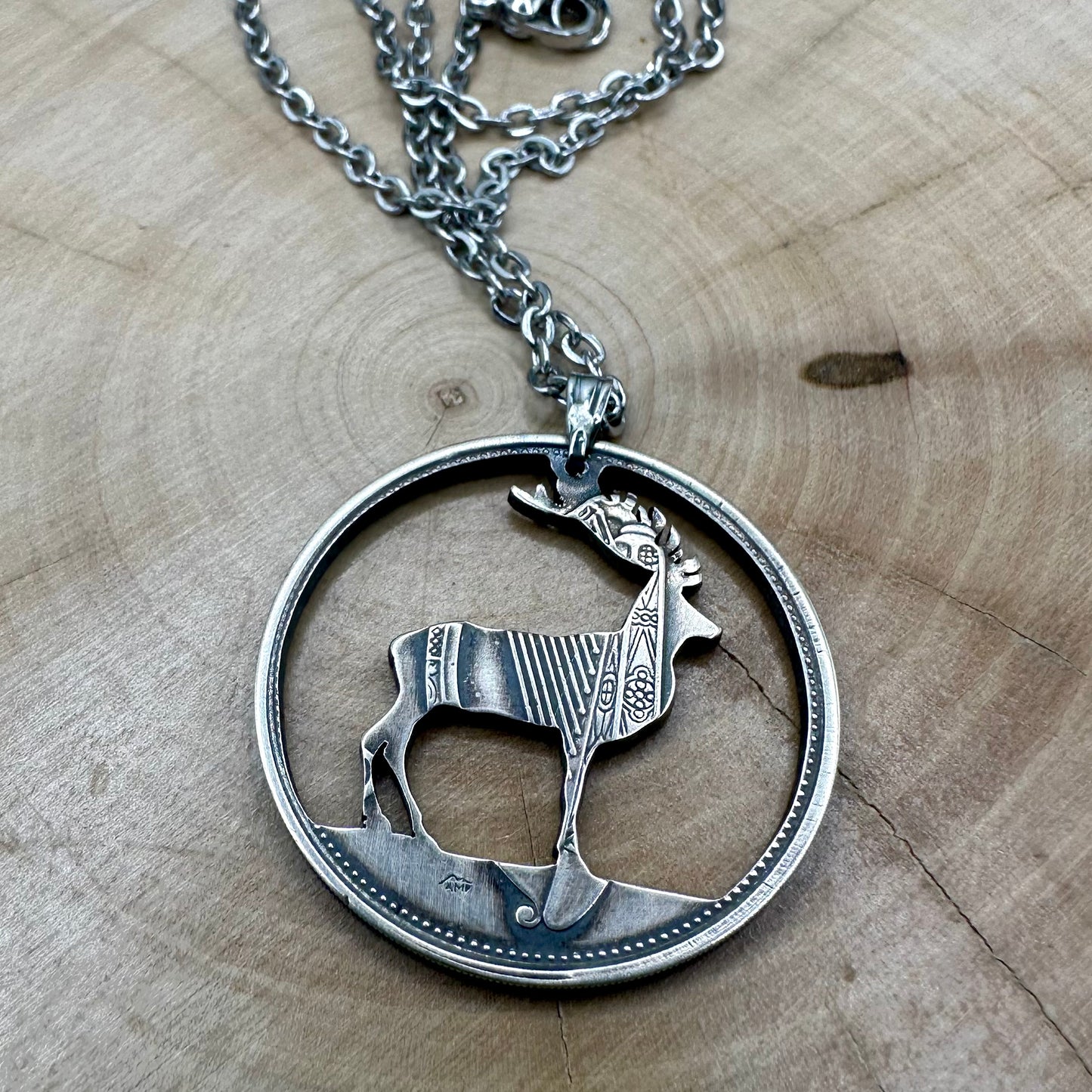 Ireland Red Deer Hand Cut Coin Necklace back on a wood round. - Mountainstruck Coin Jewelry