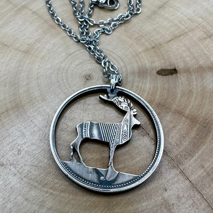 Ireland Red Deer Hand Cut Coin Necklace back on a wood round. - Mountainstruck Coin Jewelry