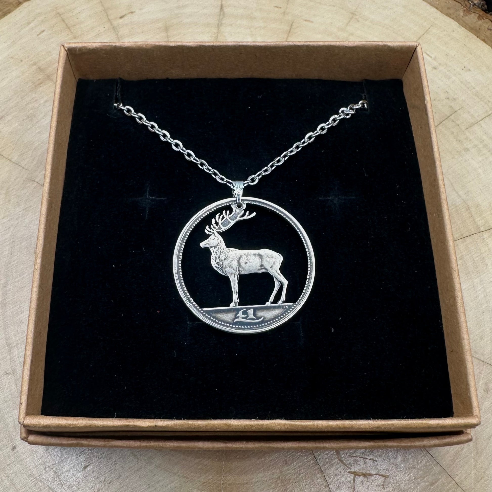 Ireland Red Deer Hand Cut Coin Necklace on a black velvet background in a brown kraft box on a wood round. - Mountainstruck Coin Jewelry