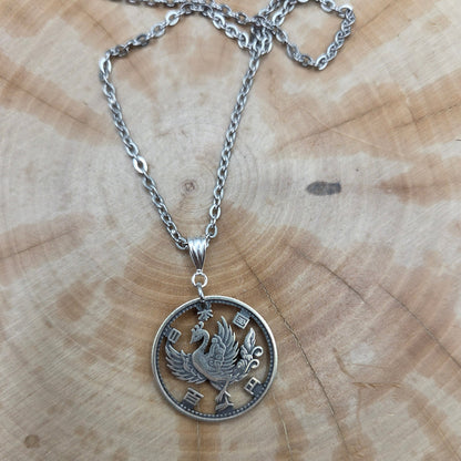 Japan Phoenix 100 Yen Silver Hand Cut Coin Necklace on a wood background. - Mountainstruck Coin Jewelry
