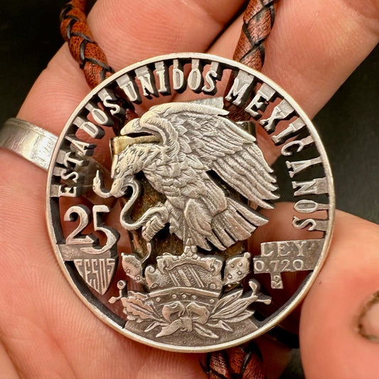 Mexico Silver 25 Pesos Hand Cut Coin Bolo Tie with darker brown leather cord on a hand for display. - Mountainstruck Coin Jewelry