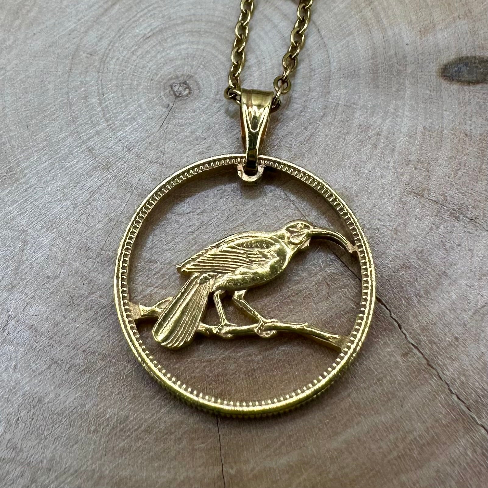 New Zealand Huia Bird 6 Pence Silver  24k Gold Plated Hand Cut Coin Necklace on a black velvet background. - Mountainstruck Coin Jewelry