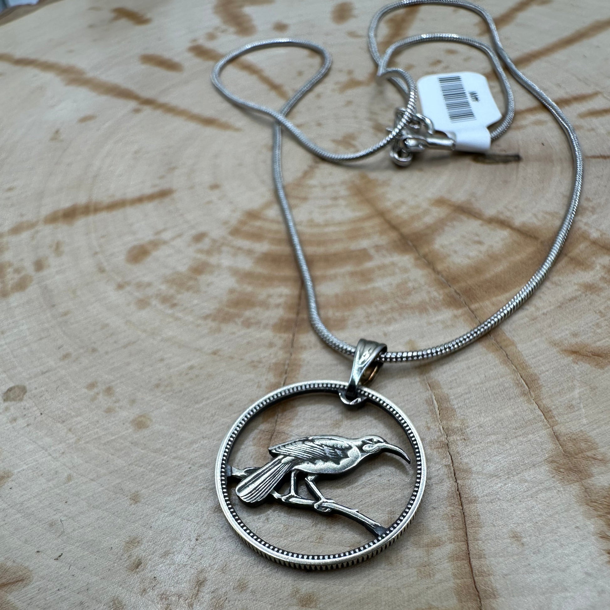 Huia Bird Silver New Zealand 6 Pence Hand Cut Coin Necklace on a black velvet background. - Mountainstruck Coin Jewelry