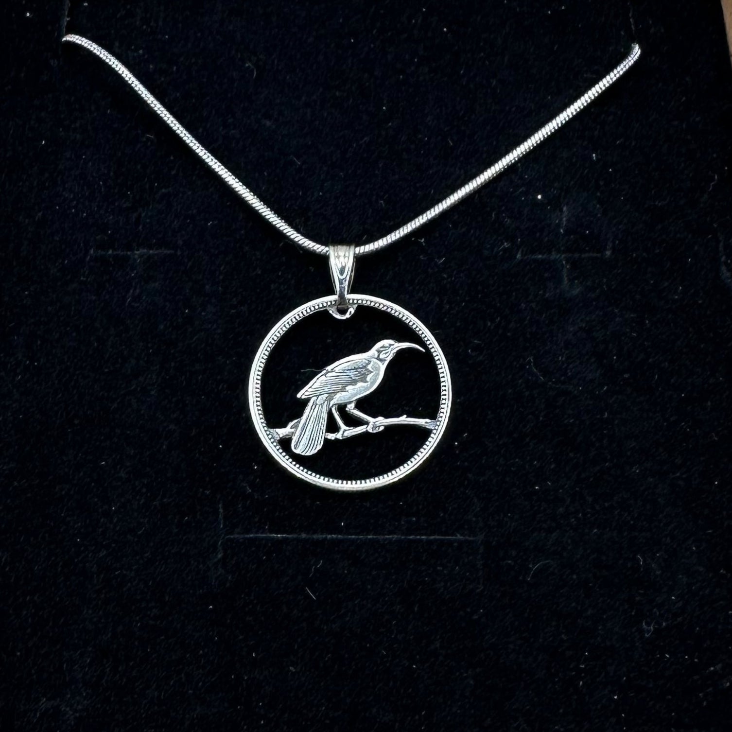 Huia Bird Silver New Zealand 6 Pence Hand Cut Coin Necklace on a black velvet background. - Mountainstruck Coin Jewelry