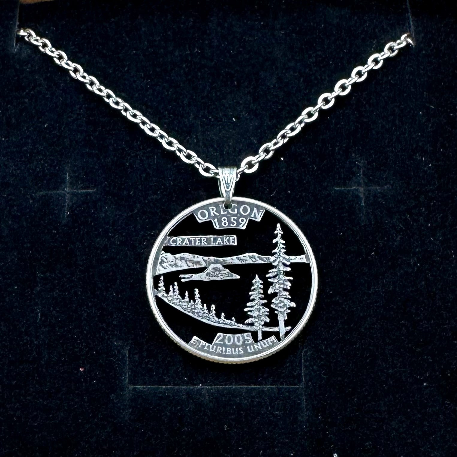 Oregon State Quarter Hand Cut Coin Necklace with a stainless chain on a black velvet background. - Mountainstruck Coin Jewelry