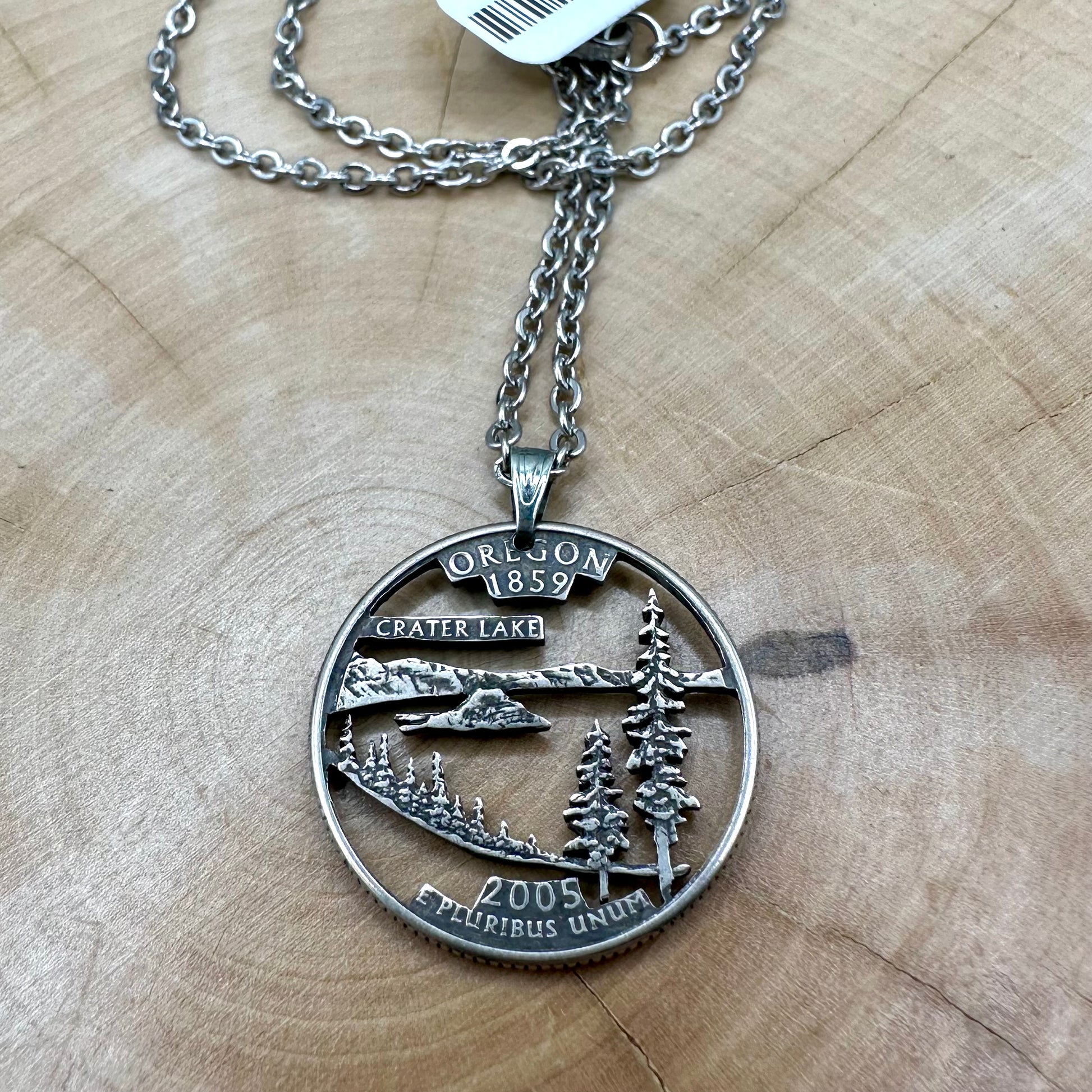 Oregon State Quarter Hand Cut Coin Necklace with a stainless steel chain on a wood background. - Mountainstruck Coin Jewelry