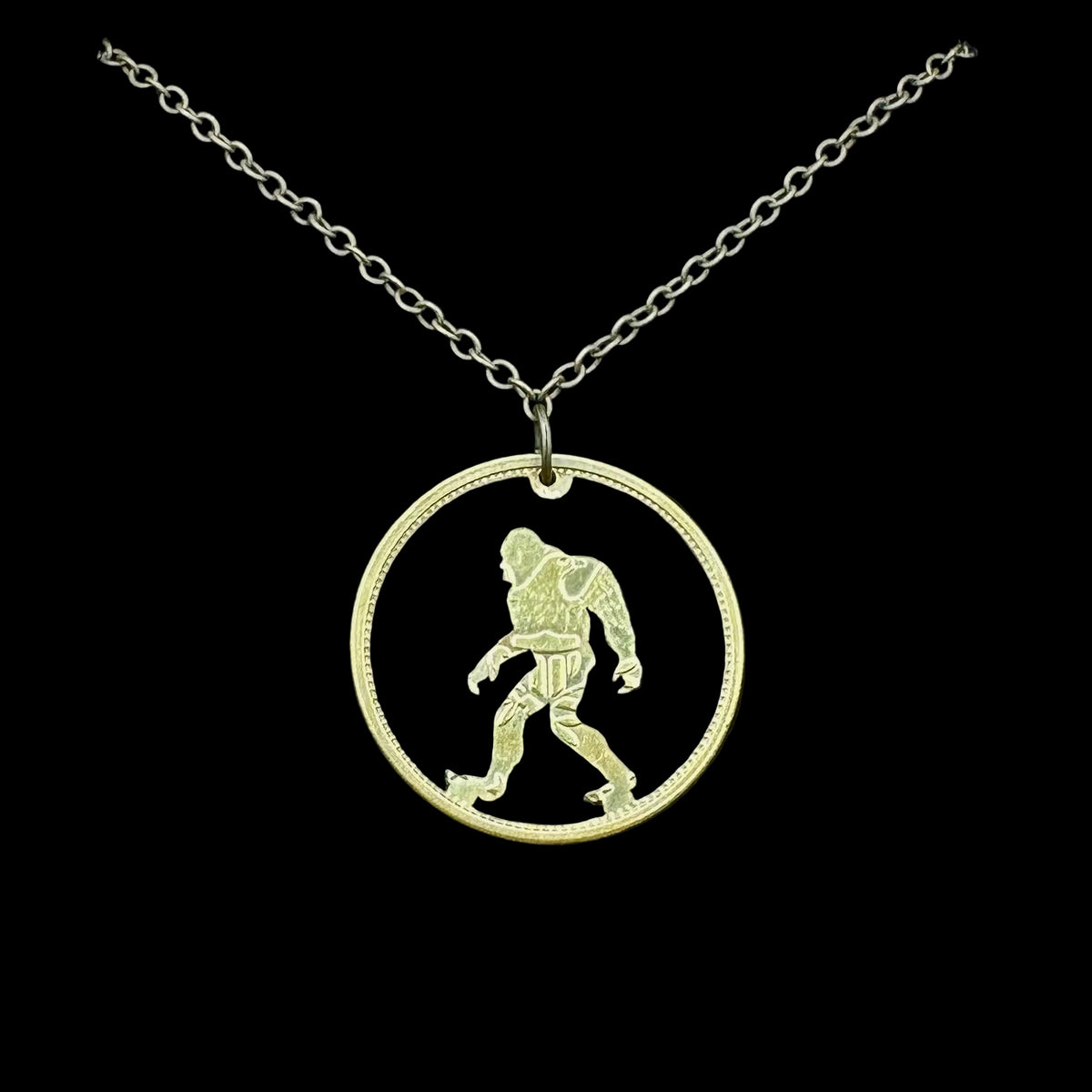 Sasquatch Hand Cut Token Necklace with a bronze chain on a black velvet background. - Mountainstruck Coin Jewelry