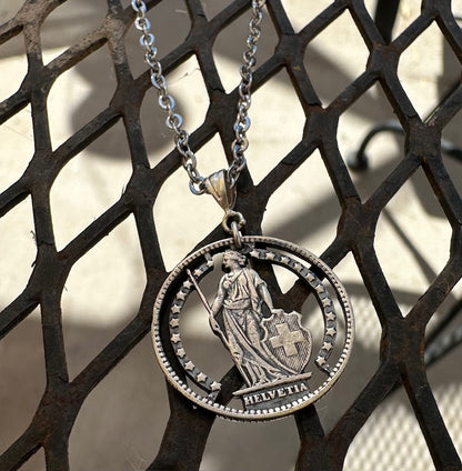 Silver Lady Swiss 1 Franc Hand Cut Coin Necklace on a diamond shaped metal grate. - Mountainstruck Coin Jewelry