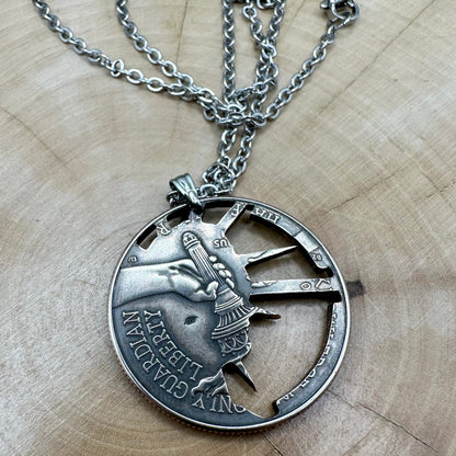 U.S. Half Dollar Hand Cut Necklace (front) with a stainless chain light wood background. - Mountainstruck Coin Jewelry