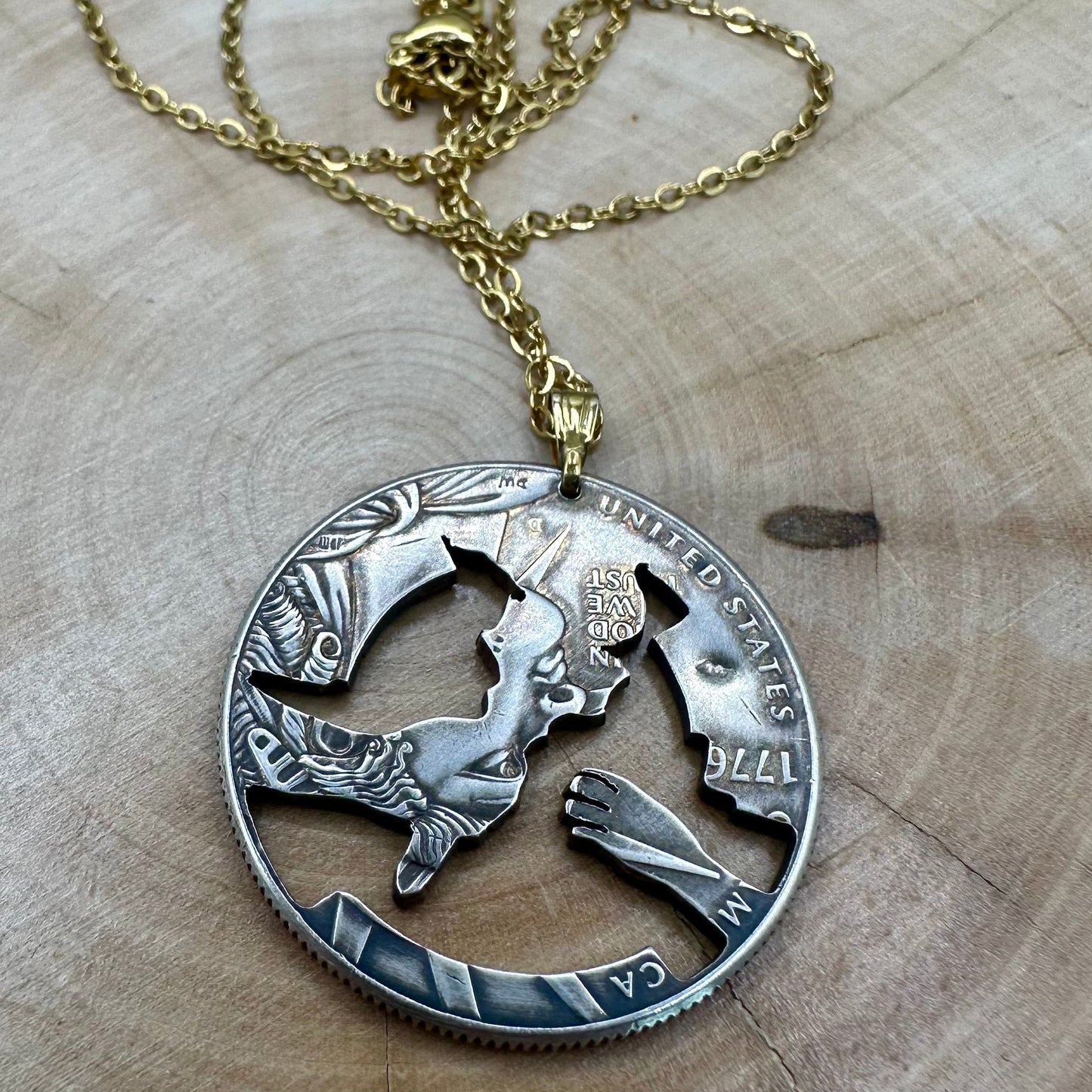 U.S. 2026 Half Dollar Hand Cut Coin Necklace (reverse) 24k gold plated torch with a gold plated chain on a light wood round. - Mountainstruck Coin Jewelry
