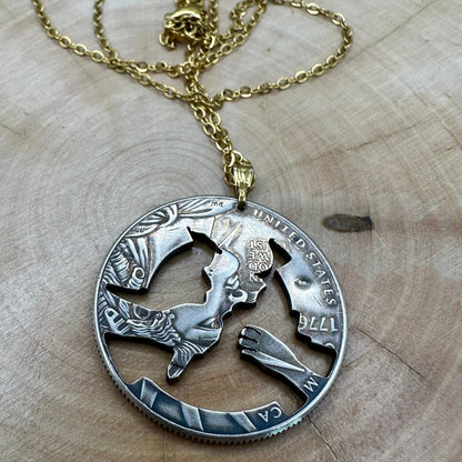 U.S. 2026 Half Dollar Hand Cut Coin Necklace (reverse) 24k gold plated torch with a gold plated chain on a light wood round. - Mountainstruck Coin Jewelry