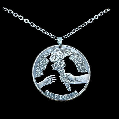 U.S. 2026 Half Dollar Hand Cut Coin Necklace (reverse) with a stainless chain on a black velvet background. - Mountainstruck Coin Jewelry