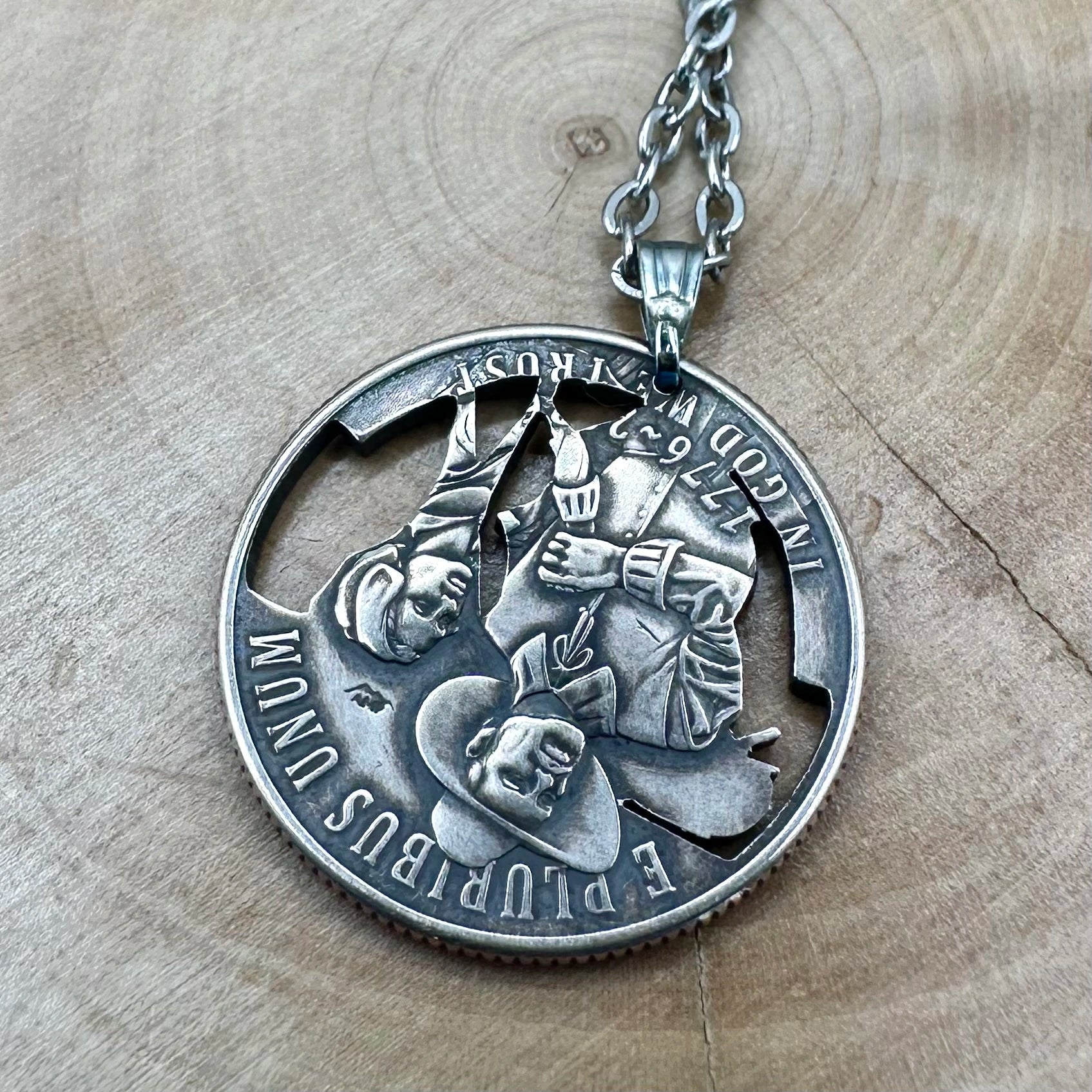 U.S. 2026 "Mayflower" Quarter Hand Cut Coin Necklace back with a stainless chain on a wood background. - Mountainstruck Coin Jewelry