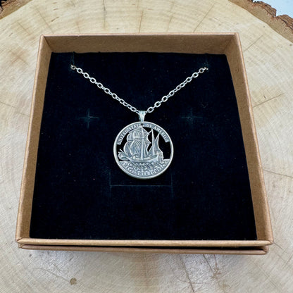U.S. 2026 "Mayflower" Quarter Hand Cut Coin Necklace with a stainless chain on a black velvet background in a brown kraft box on a wood round. - Mountainstruck Coin Jewelry