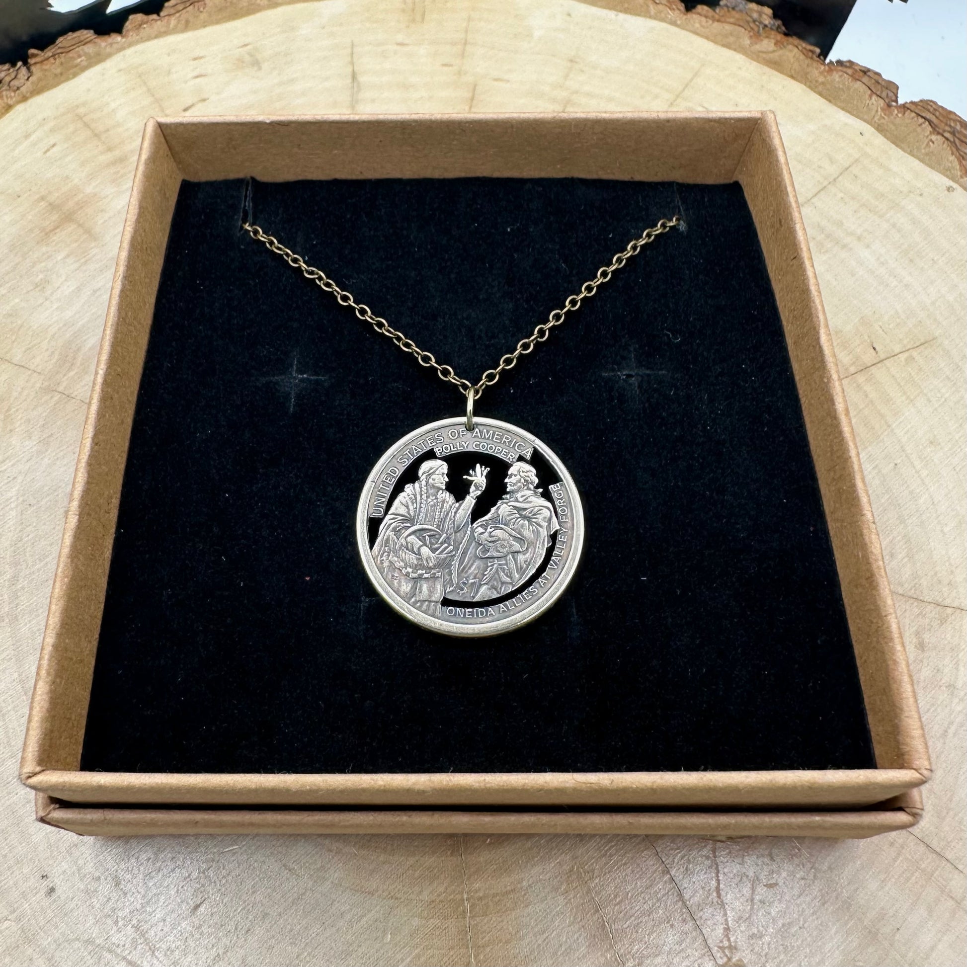U.S. 2026 Oneida Allies 1 Dollar Hand Cut Coin Necklace with a bronze chain on a black velvet background in a brown kraft box on a wood round. - Mountainstruck Coin Jewelry