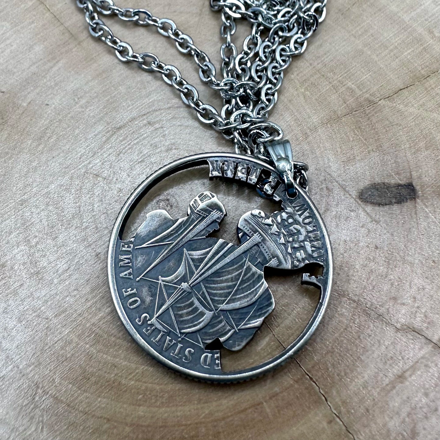U.S. 2026 "Pilgrim" Quarter Hand Cut Coin Necklace back with a stainless chain on a wood round. -Mountainstruck Coin Jewelry